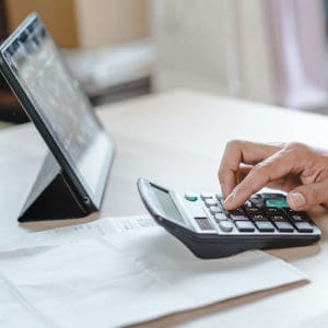 person having a calculator, tablet and papaer